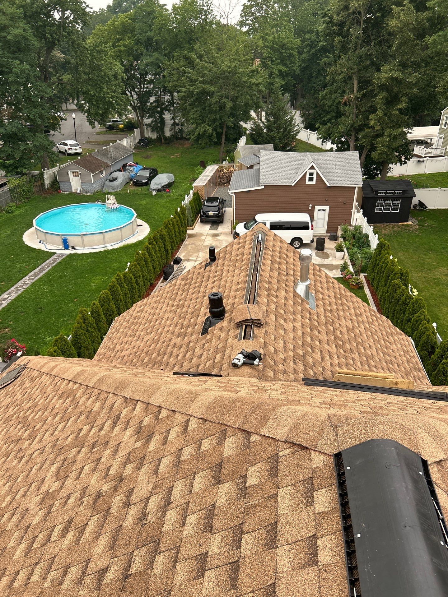 Point-of-view from the ridge of a completed Victorian roof looking down the slope over the North Jersey neighborhood