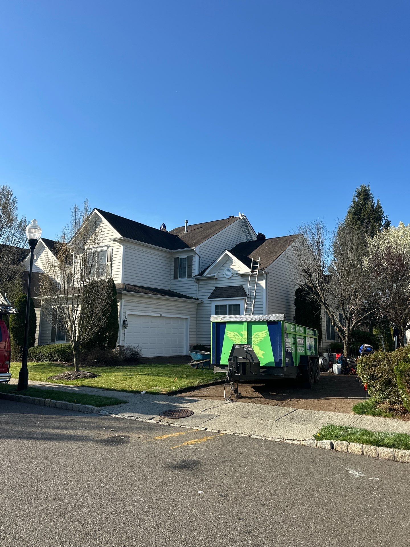 LGM Roofing dumpster trailer and crew van staged in the driveway of a North Jersey colonial