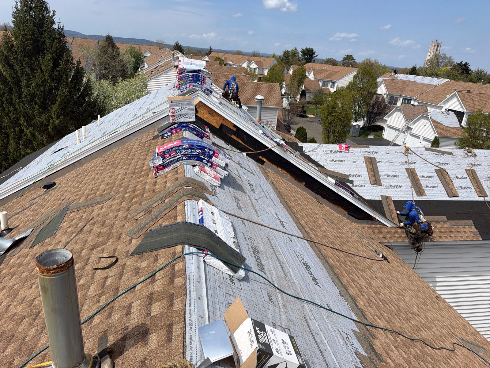 Suburban roof mid-installation with half the surface shingled in GAF Timberline HDZ and half still FeltBuster