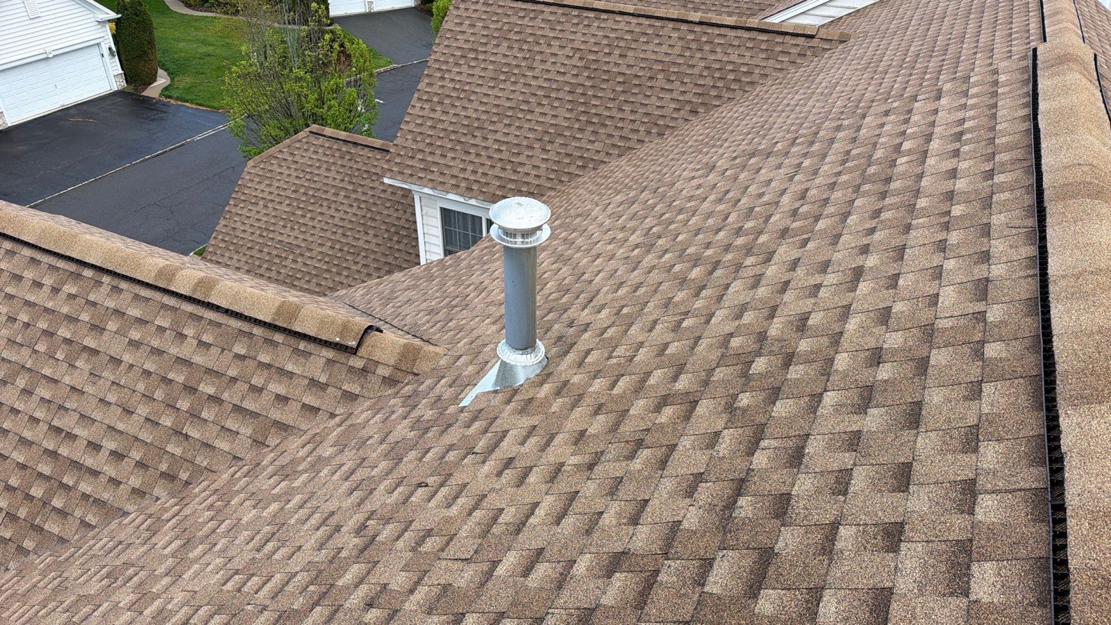 Drone view of a suburban roof nearing completion with new GAF shingles covering most of the surface