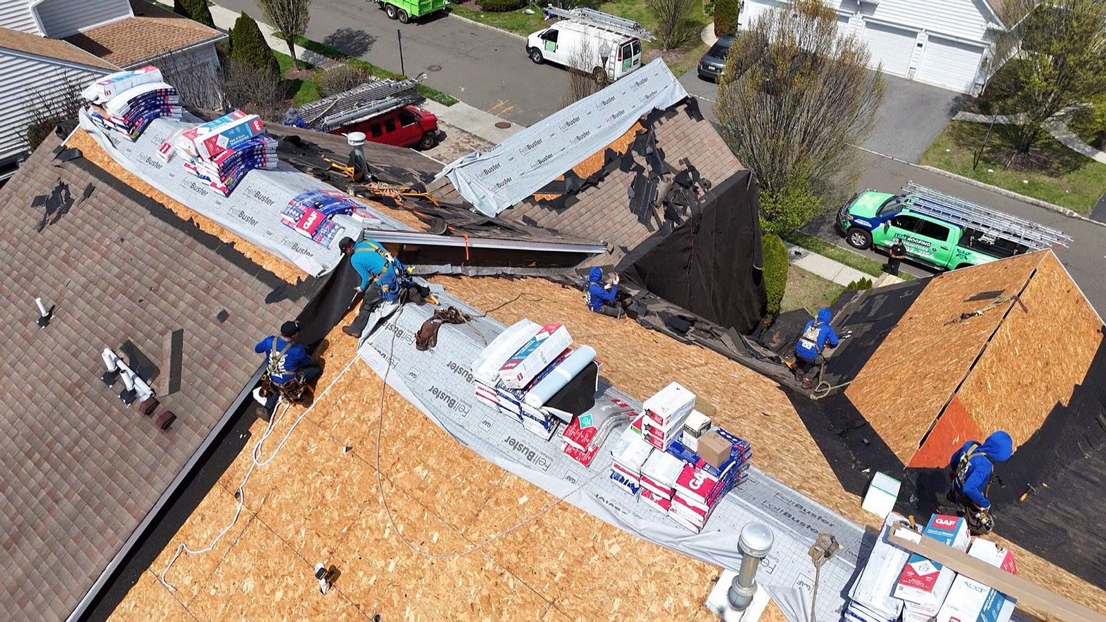 Aerial shot of a half-stripped suburban roof with FeltBuster underlayment on one side and old shingles on the other