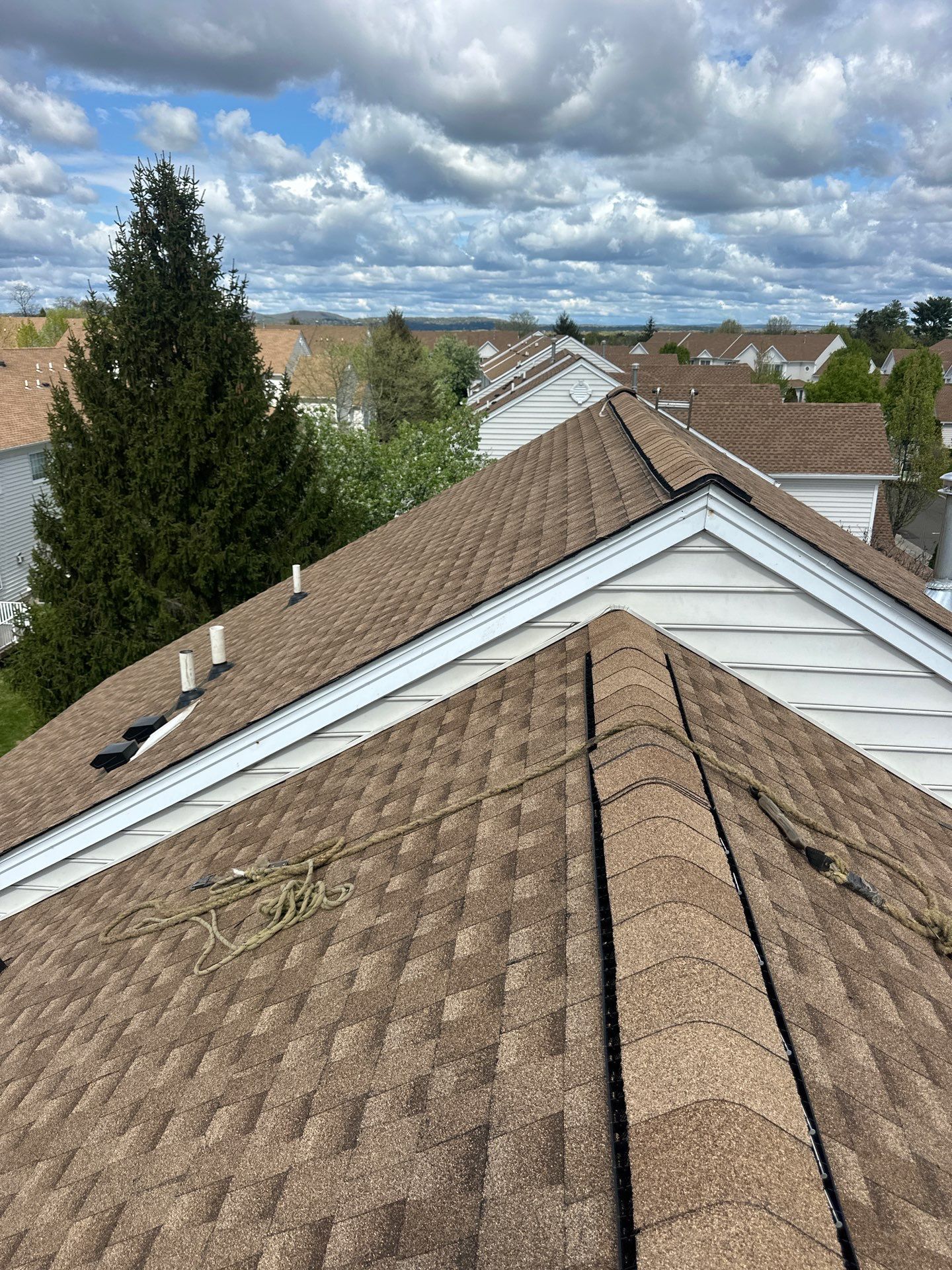 LGM crew members installing GAF shingles over FeltBuster on a steep suburban roof section