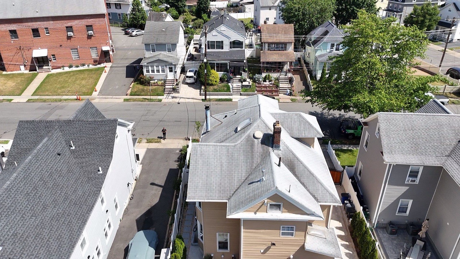 Completed tan shingle roof on a Victorian home with red shutters and bay windows in North Jersey