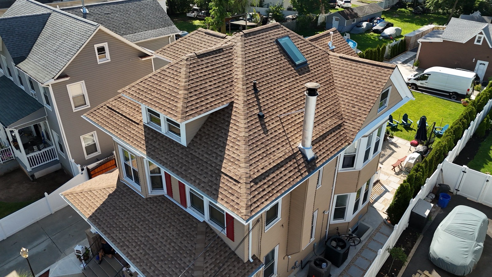 Final drone overhead of a completed Victorian roof replacement with new tan GAF shingles and skylight