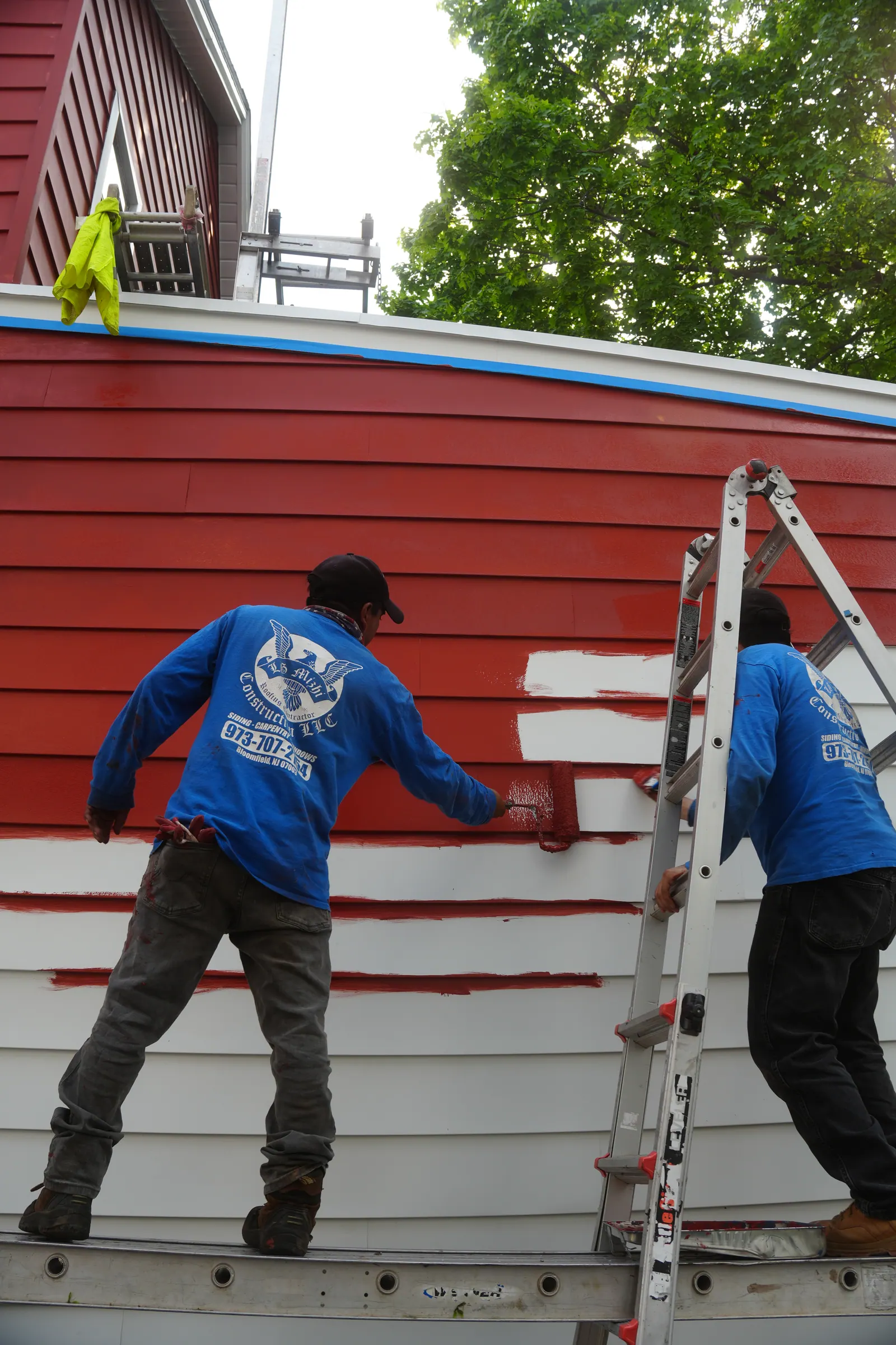 Wide view of an LGM crew working the exterior of a red-sided New Jersey home