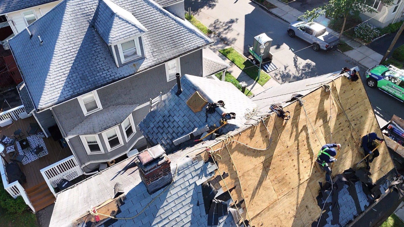 Drone view of LGM crew resheathing a roof with new plywood alongside the LGM branded truck