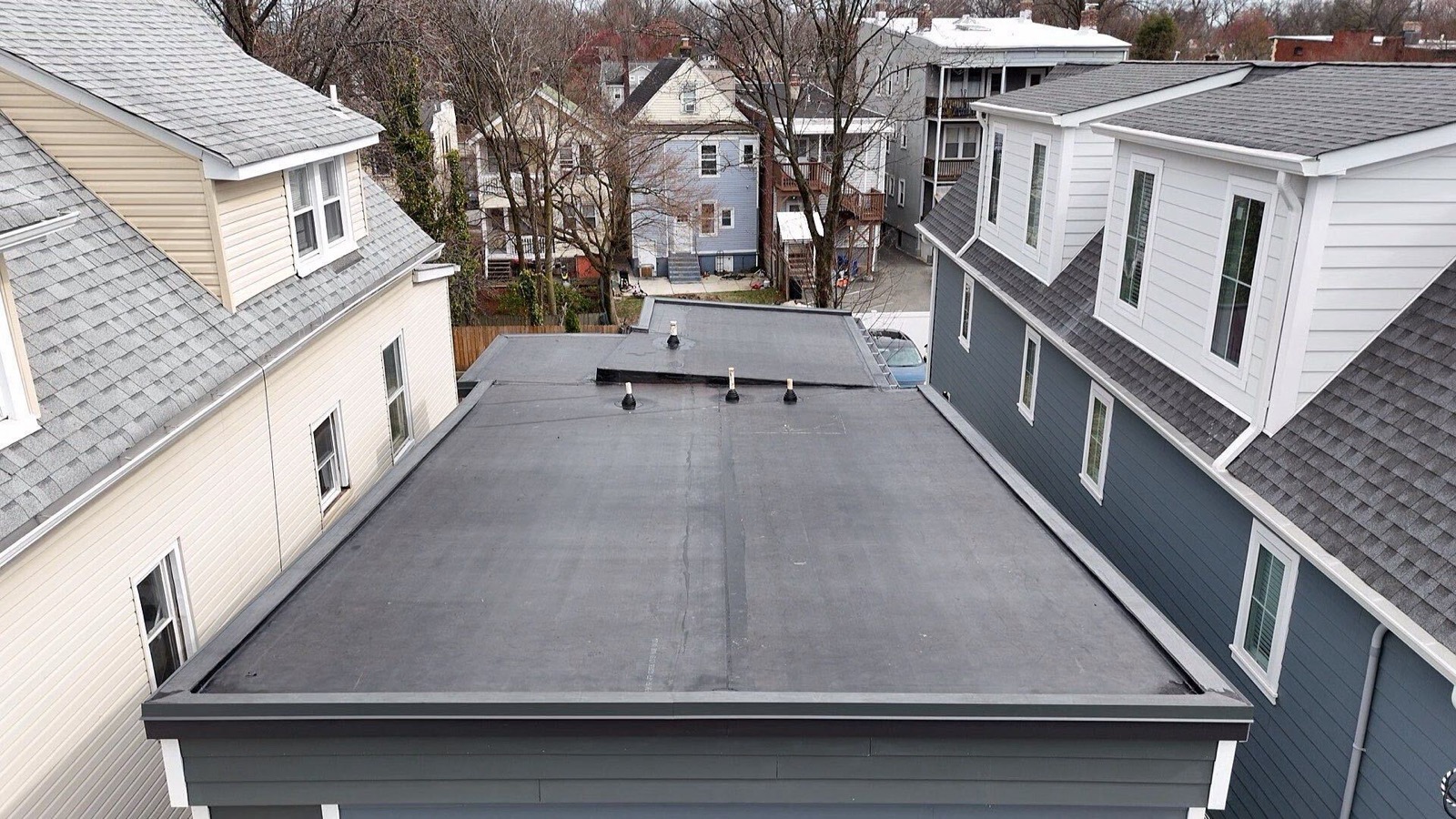Drone view of a completed EPDM flat roof with pipe penetrations on a North Jersey row house