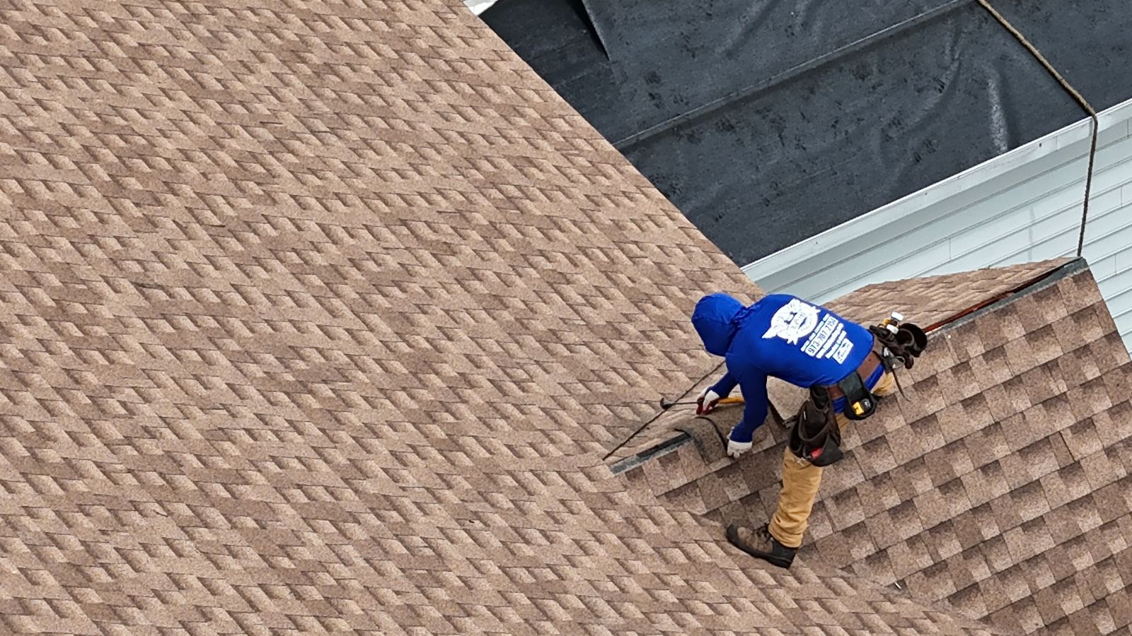 Aerial drone view of an LGM Roofing crew member installing shingles on a roof