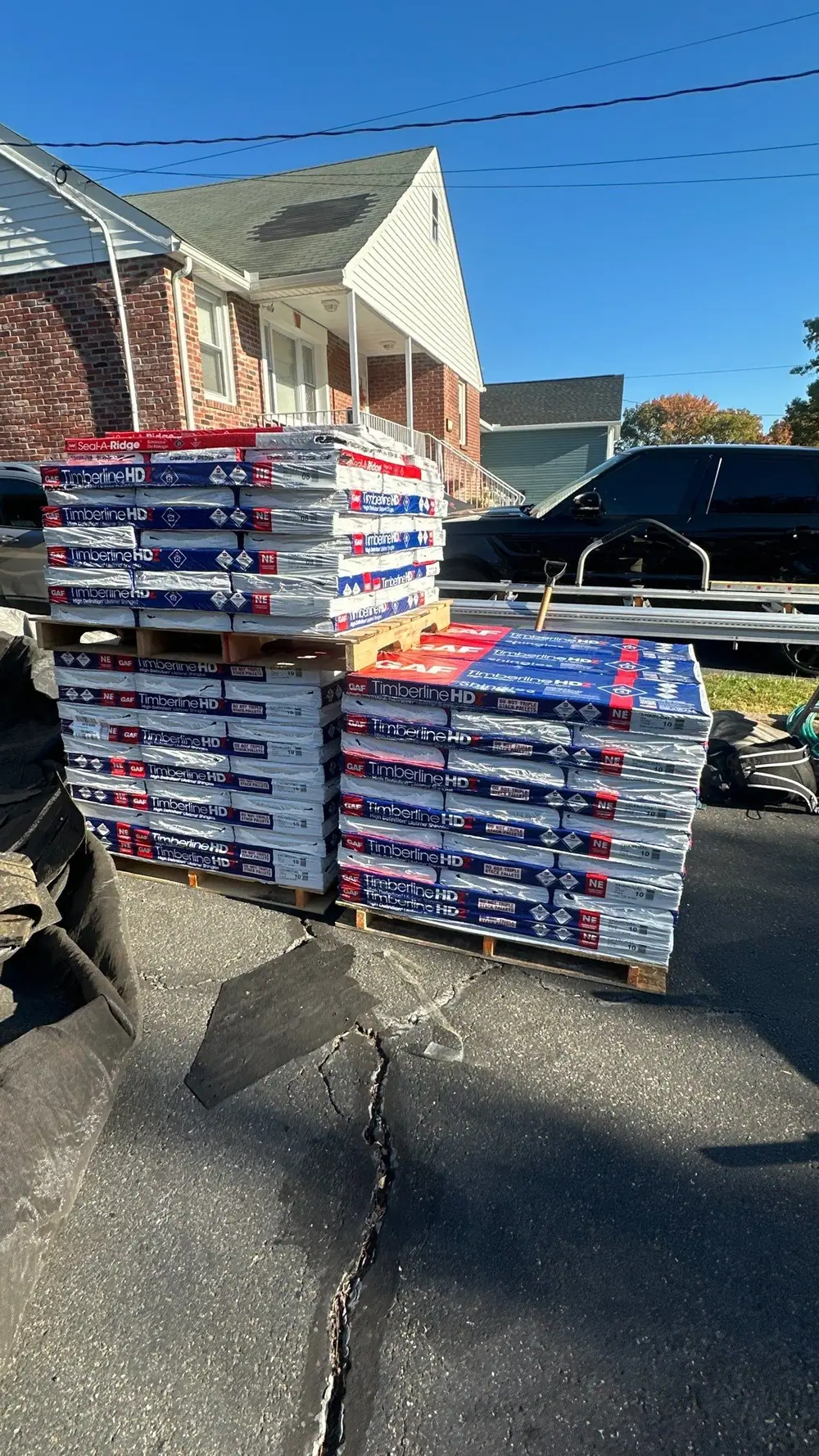 Pallet of GAF shingle bundles staged in a driveway before an LGM roof replacement