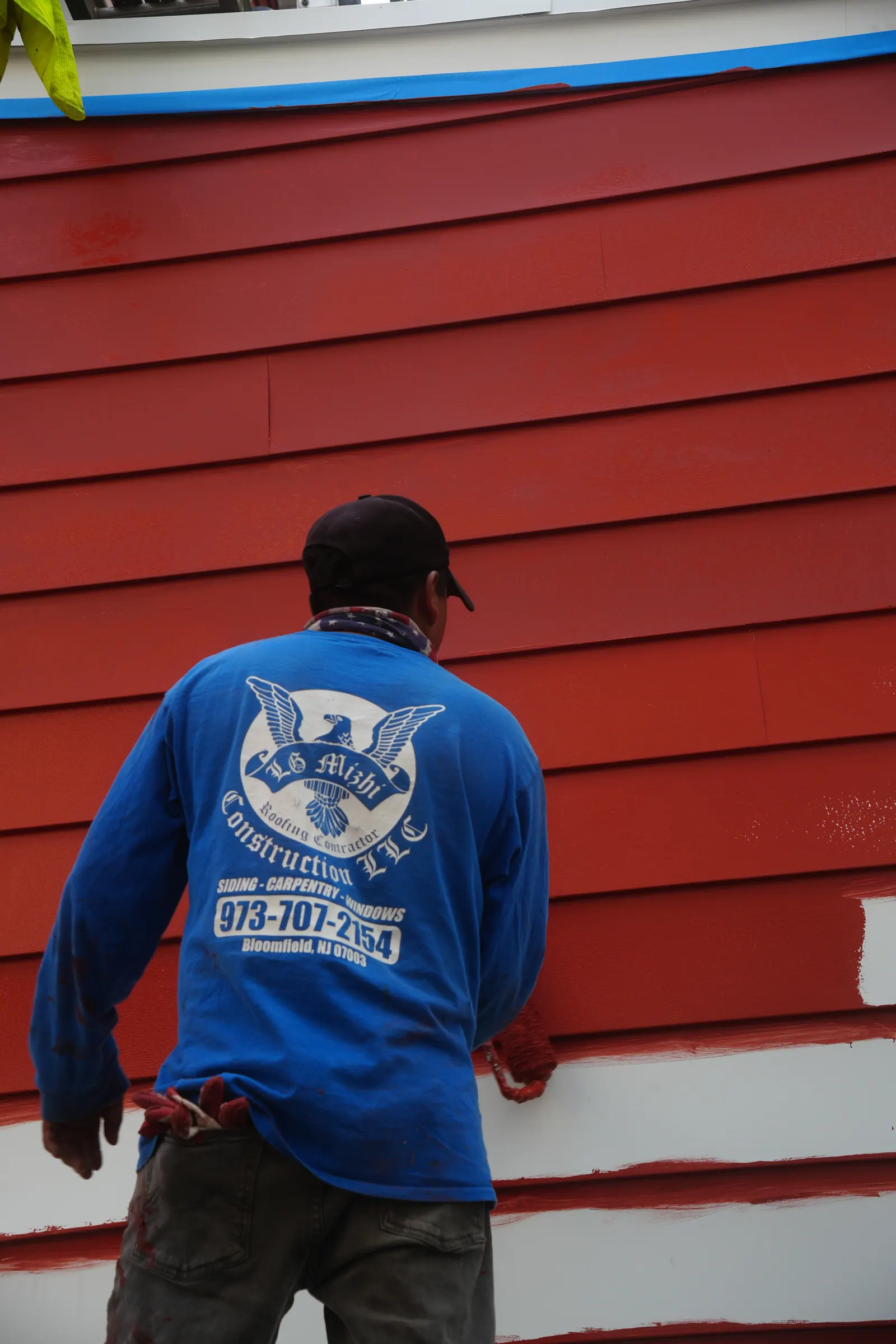 Red siding courses installed across the side elevation of a New Jersey home