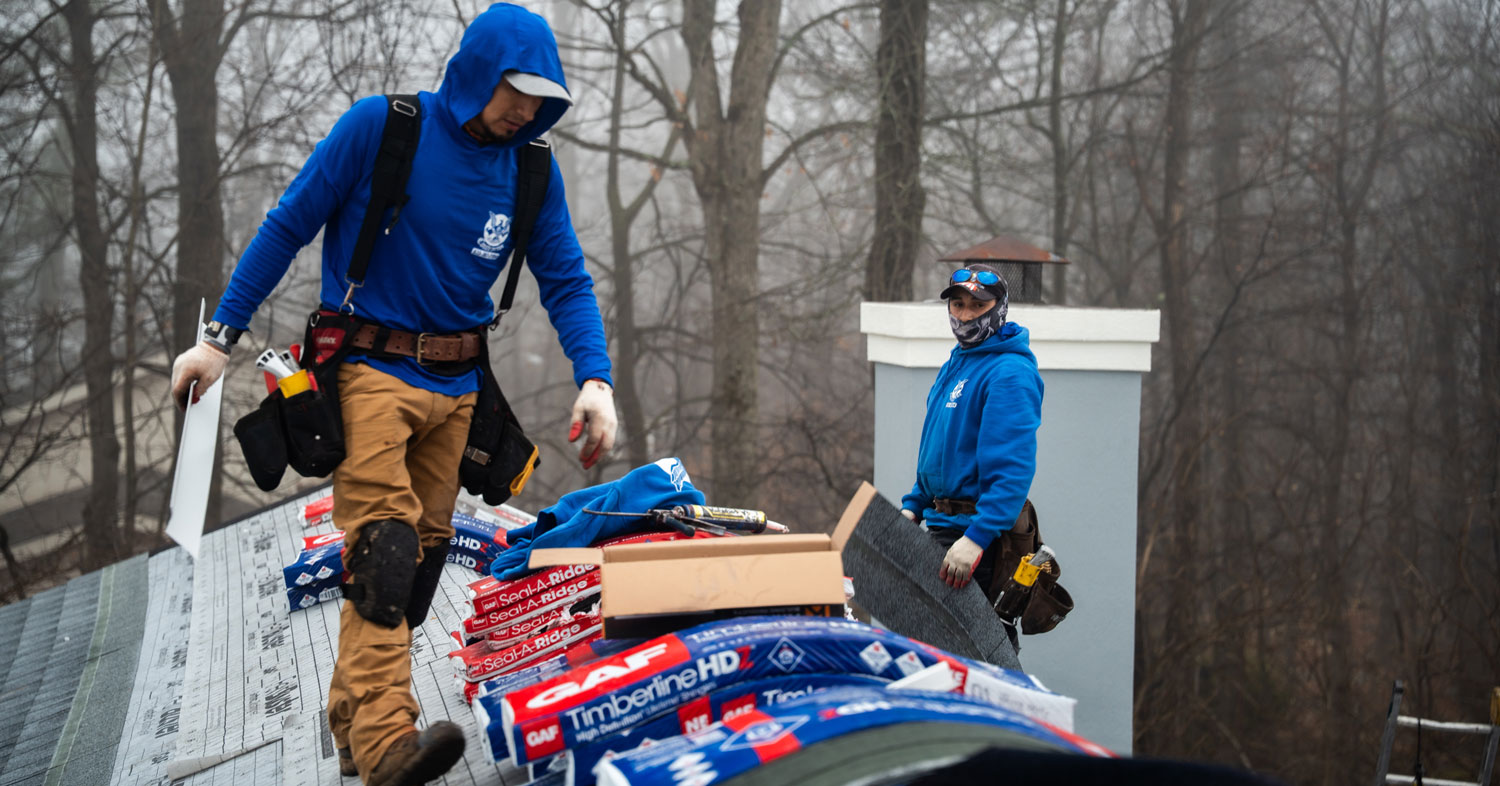 LGM Roofing installers laying GAF Timberline HDZ shingles on a wooded North Jersey home